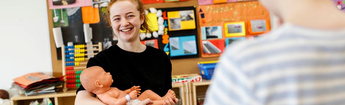 An Early Childhood care Student poses with a Baby Doll