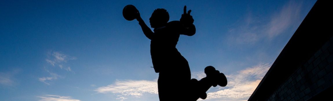 Silhouette of a Sports student jumping in the air with a basketball. Evening sky in the background