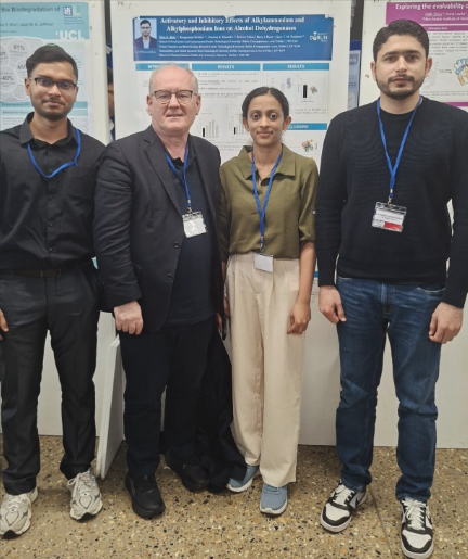 A group of researchers in front of posters at an academic conference.