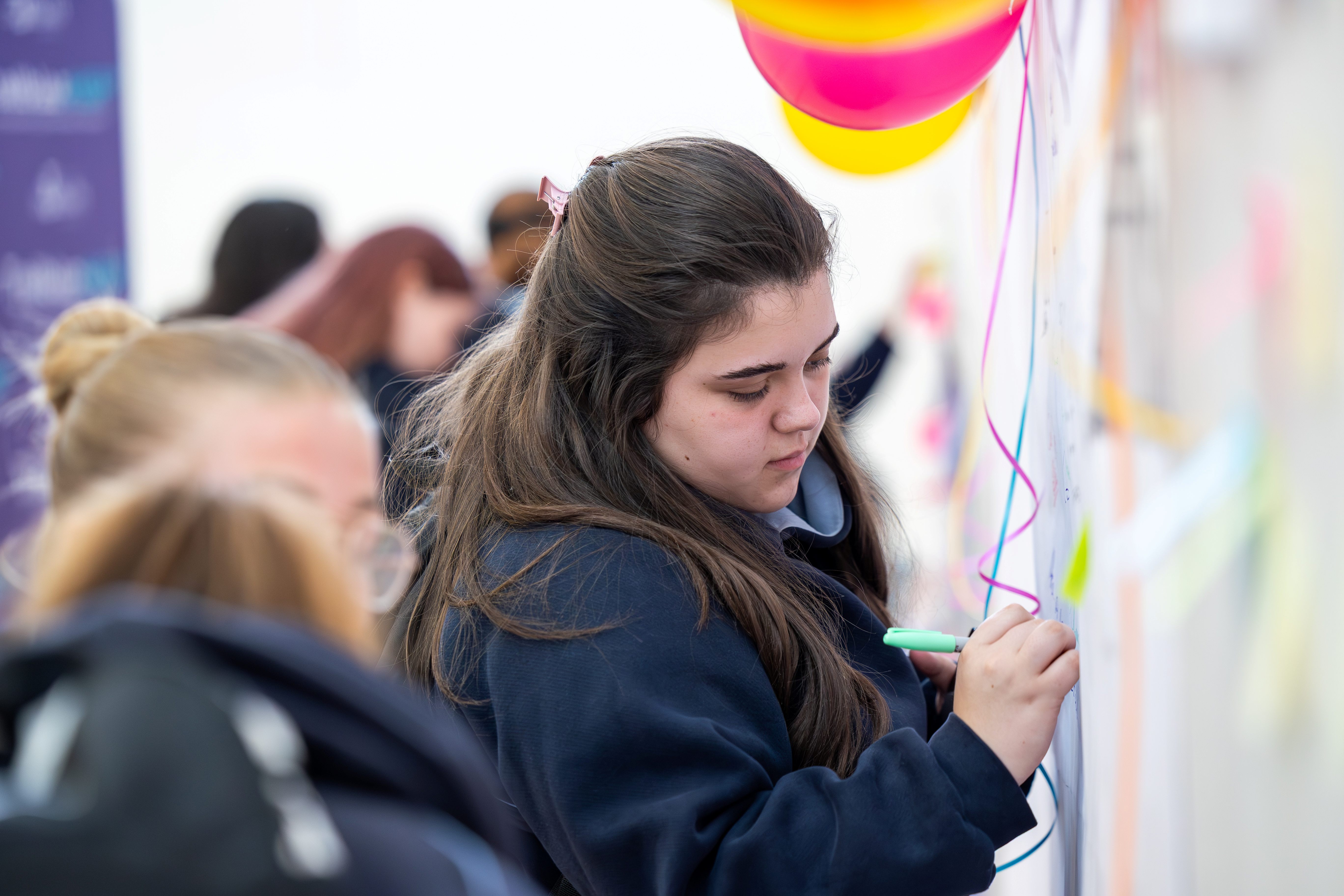 A student writing on an interactive display wall at the Jobs of the Future Festival