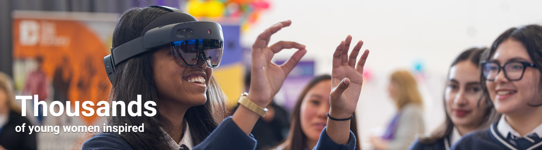 A young girl tries VR goggles while her peers watch