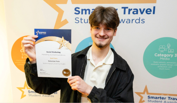 male student holds certificate at smarter travel awards backdrop