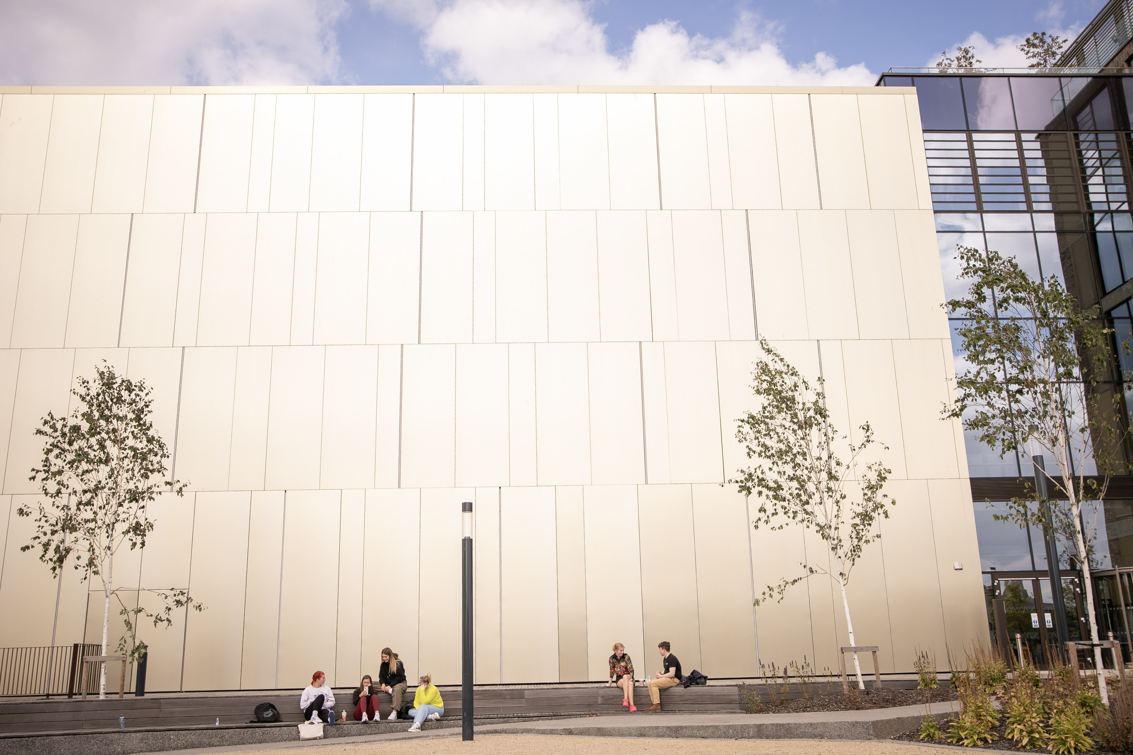 east quad building grangegorman sheer gold front. some people sitting in background.