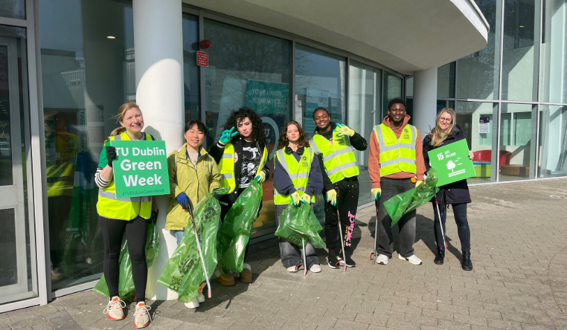 7 PEOPLE hold bags of litter, litter picks and SDG Life on Land sign