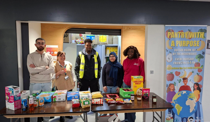 three woman and two men stand behind the food pantry counter