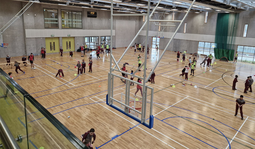 large group of primary school students in a basket ball hall - they are wearing wine coloured uniform