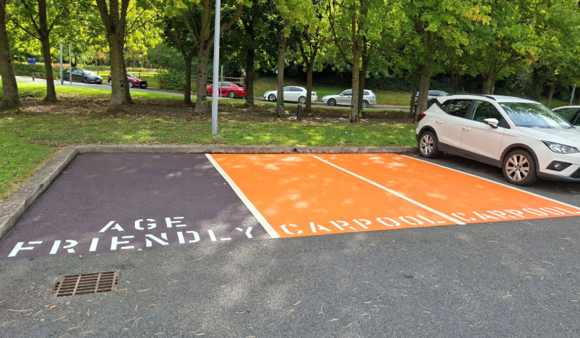 vacant orange car park spaces that reads 'car pool', adjacent to another that reads 'age-friendly'