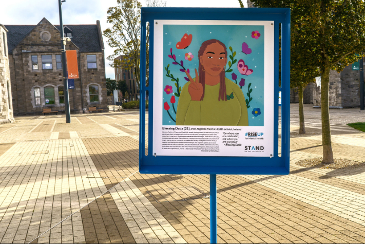 STAND festival sign with graphic painting of a girl on a blue background outdoors at TU Dublin campus