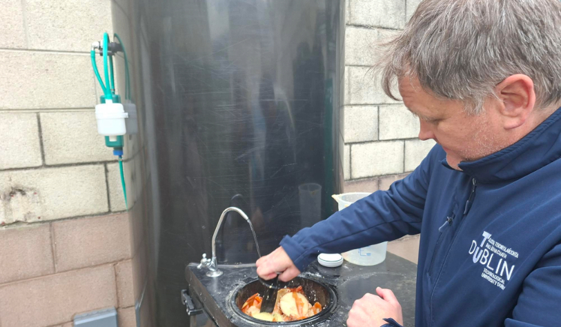 white man pushes food waste into what looks like a sink inside in a barrel