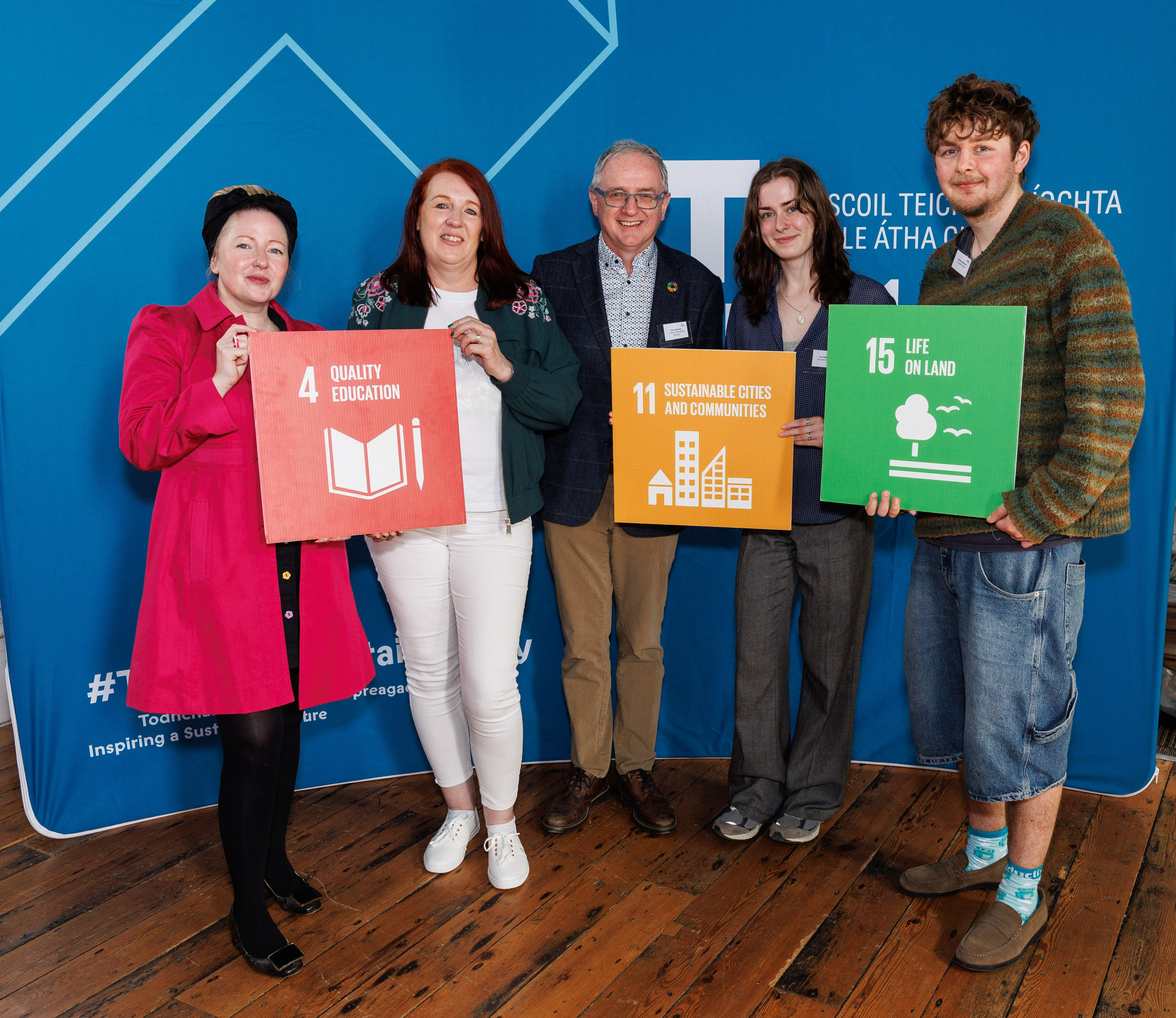 Five people holding SDG signs