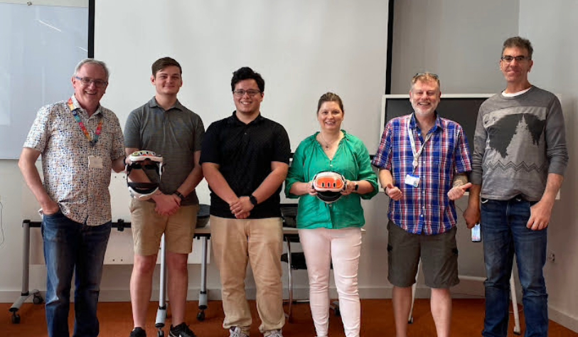5 male and 1 female smile for camera two are holding Mixed Reality goggles