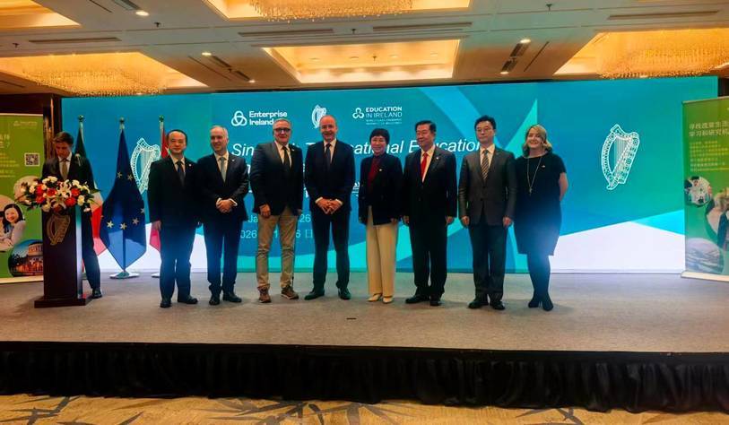 A group of people pose for a photo in front of a Government of Ireland banner