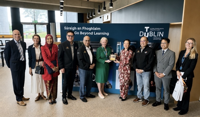 Group of nine people standing together at TU Dublin’s Grangegorman campus, with representatives from Malaysia and TU Dublin posing in front of a TU Dublin “Go Beyond Learning” display.