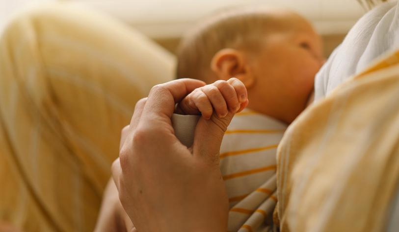 Newborn baby drinking milk from mothers breast. Portrait of mom and breastfeeding baby.