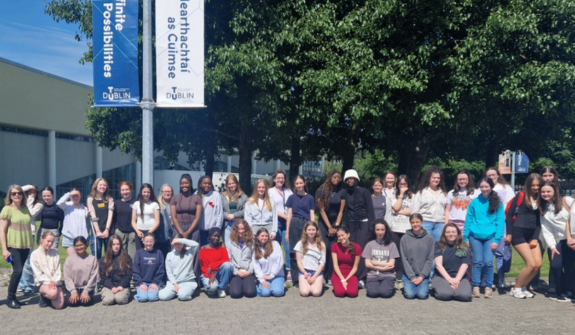 A group of young women pose for a photo under a TU Dublin branded banner