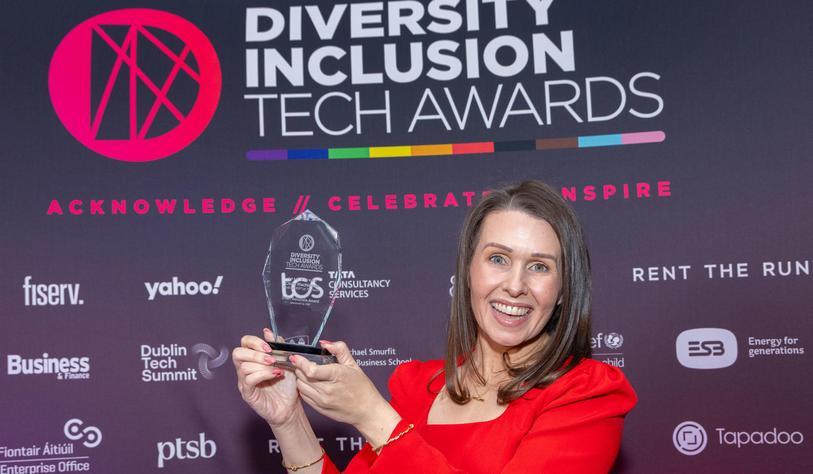 A person holds a trophy in front of a banner that says 2026 Diversity Inclusion Tech Awards.