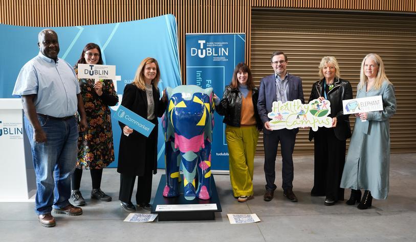 A group of people pose with a brightly coloured ceramic elephant