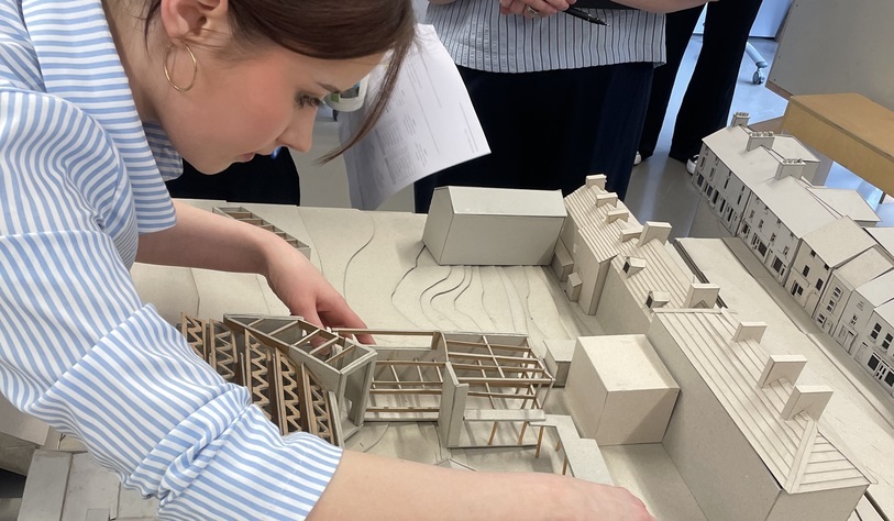 A TU Dublin student examines a detailed scale model of Granard town centre, featuring building layouts and proposed streetscape designs.