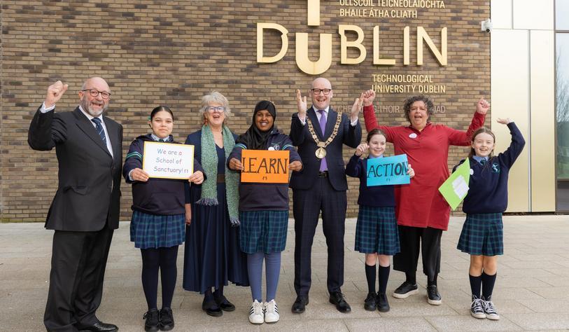A group of pupils and adults outside East Quad cheering and smiling