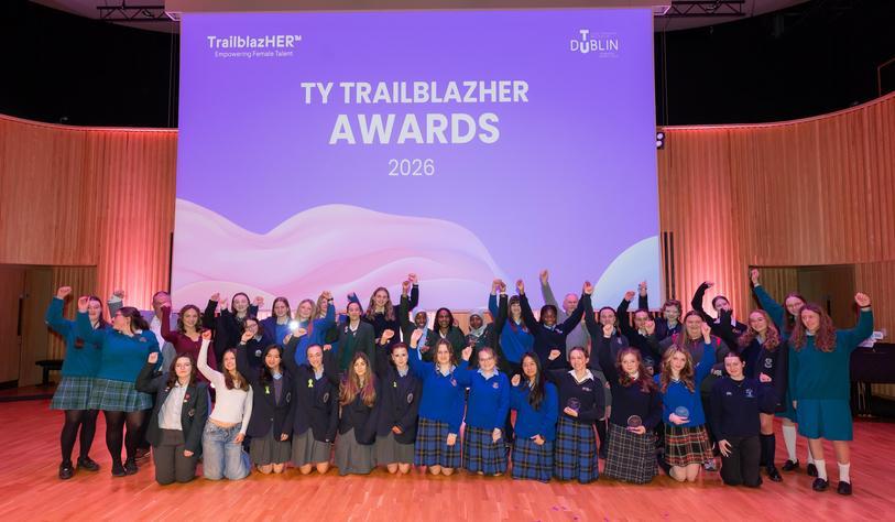 A photo of a large group of students posing in front of a banner that says2026 TY TrailblazHER Awards