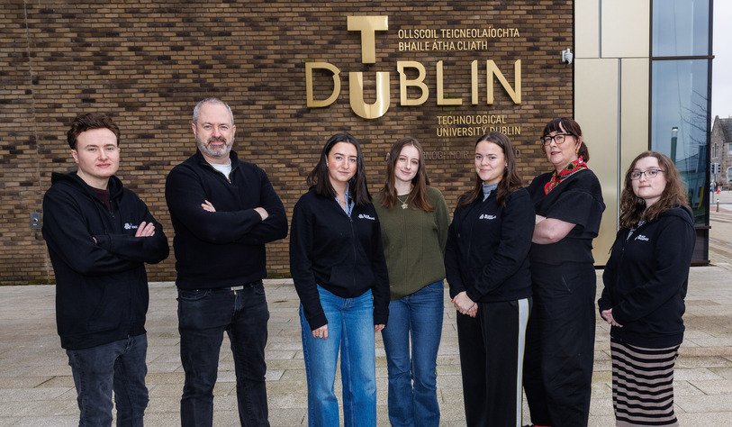 5 students and two members of staff standing in front of a brick building with a TU Dublin sign on the building