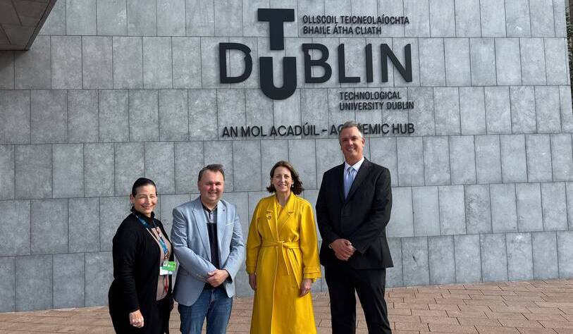 Four people stand in front of a wall with the large text “DUBLIN Technological University Dublin Academic Hub” and its Irish translation.