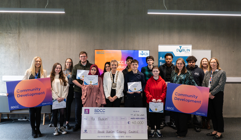 A group of people posing with certificates and a large cheque