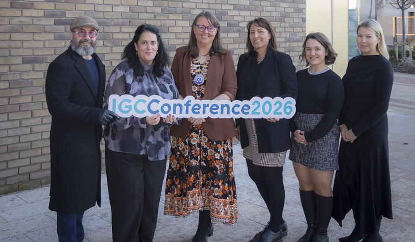 A photo of 6 people posing in front of a redbrick building holding a sign that says IGC Conference 2026