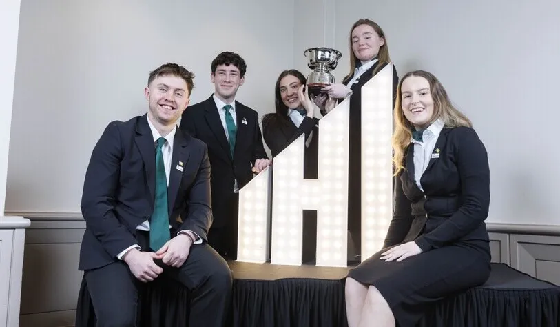 A group of five people in formal attire pose around an illuminated 